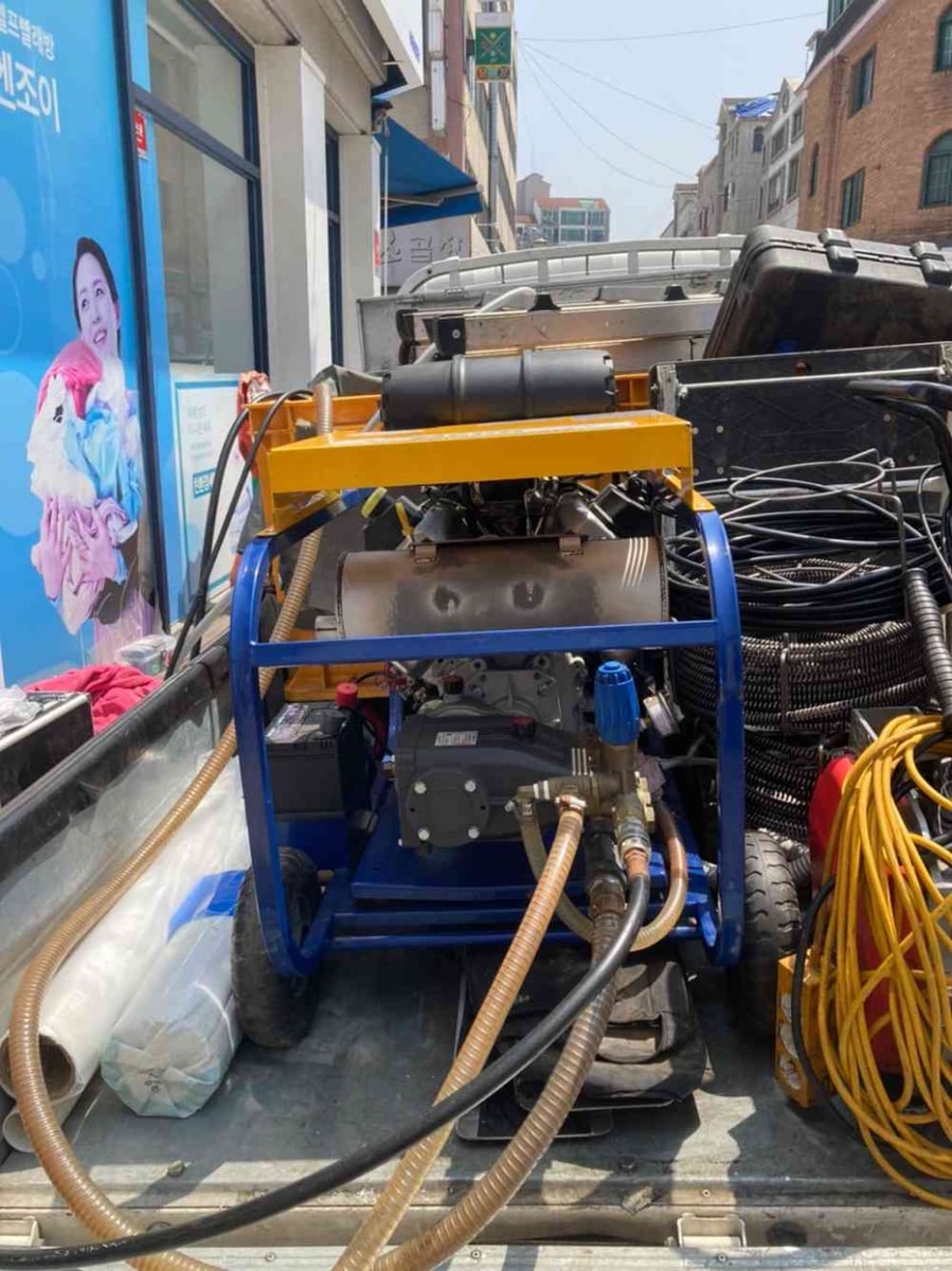 트럭에 실린 고압세척기 — 강한 수압으로 고착 슬러지를 분쇄하는 장비
